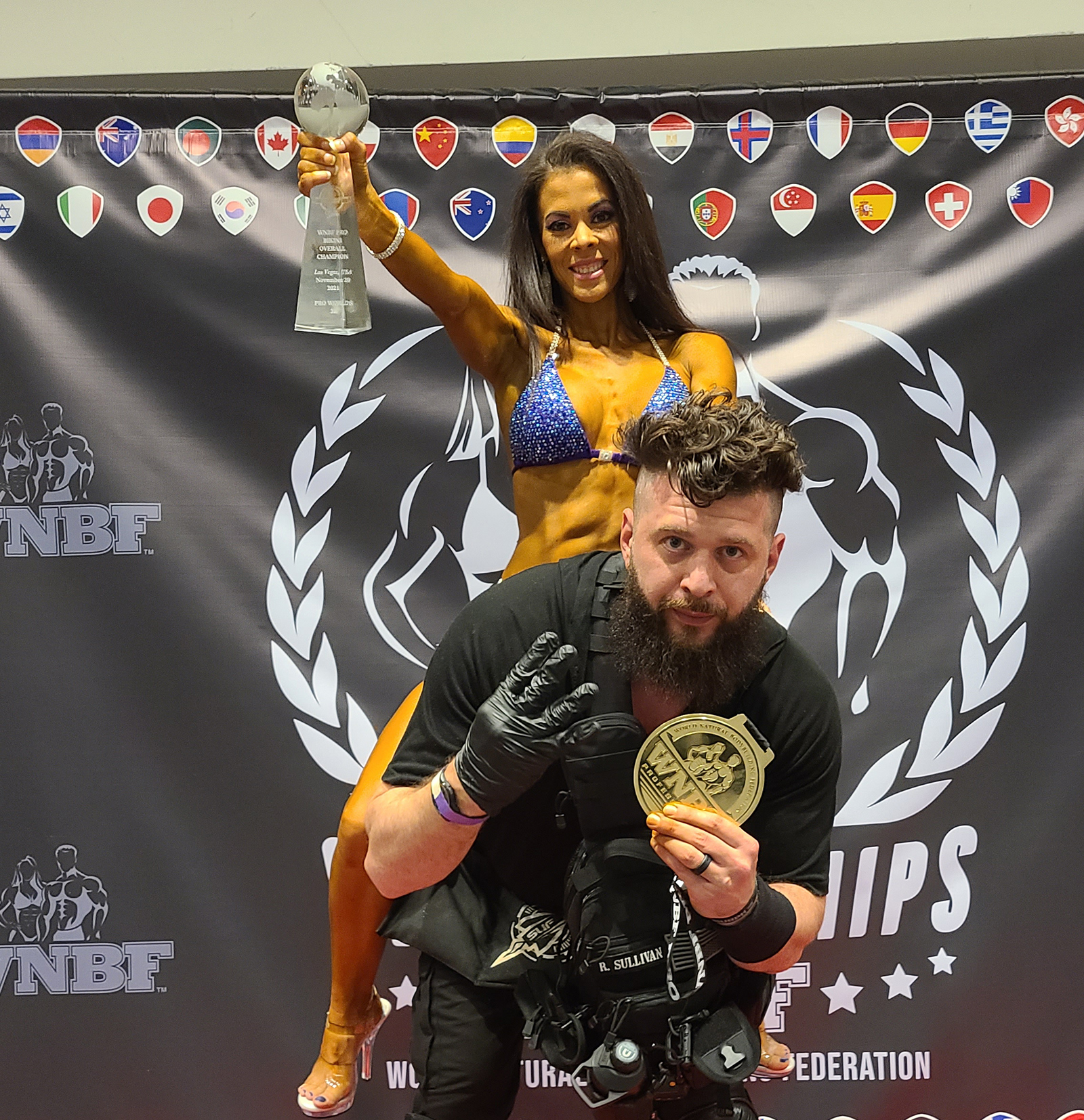Bronwyn posing with her natural bodybuilding Coach Ryan Sullivan of Team SUF after becoming the 2021 WNBF Overall Bikini World Champion